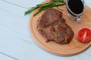 Düz uzanış, ahşap tahta üzerinde kızarmış domuz bifteği, soya sosu, biberiye ve domatesli, soldan kopyalanmış boşluk.