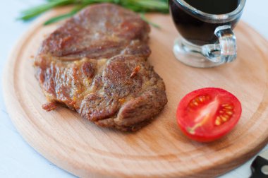 Soya sosu, biberiye ve domatesli ahşap bir tahtanın üzerinde pişmiş domuz eti.