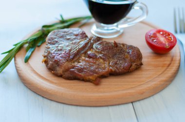 Ahşap bir tahtanın üzerinde pişmiş, ızgara domuz bifteği, soya sosu, biberiye ve domates ile birlikte fotokopi alanı ile hafif arka planda.