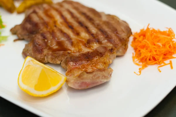 Šťavnatý a lahodný grilovaný masový steak s citrónem, mrkví, salátem a brambory. — Stock fotografie