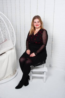 Sarı saçlı hoş bir kız yeni yıl odasında, dairesinde, evinde ya da stüdyosunda oturuyor.