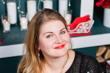 Yeni yılda çok güzel bir kadın halıda şömine ve Noel ağacının yanında.