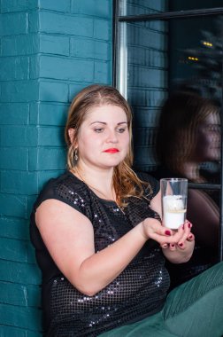 Ellerinde mumla düşünceli bir kadın pencerenin önünde oturuyor, Noel 'in içinde.