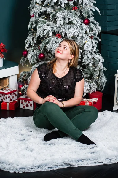 Mulher muito bonita em uma camisa preta no interior do Ano Novo oncarpet perto da lareira e árvore de Natal — Fotografia de Stock