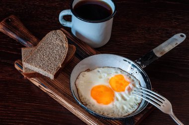 Ekmek, eski çatal, çay ile metal kupa, üst manzara ile çırpılmış yumurta.