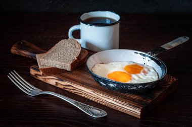 Ekmek, eski çatal, çay, yan görüş ve koyu arkaplan ile çırpılmış yumurta.