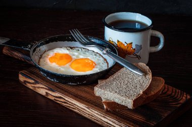 Ekmek, eski çatal, çay, yan görüş ve koyu arkaplan ile çırpılmış yumurta.
