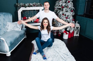 Mutlu, genç, evli bir çift şöminenin yanında ve Noel ağacının yanında