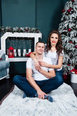 Mutlu, genç, evli bir çift şöminenin yanında ve Noel ağacının yanında