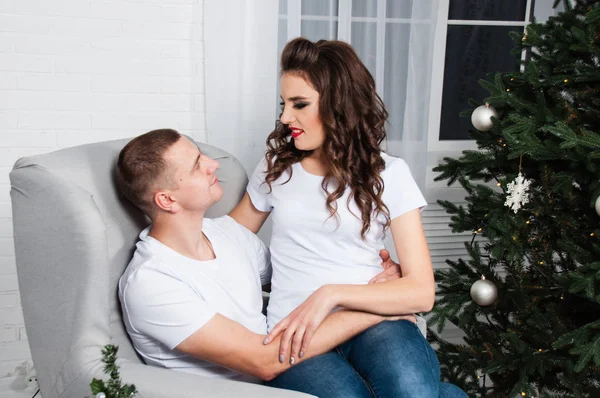 Familia feliz pareja enamorada sonriendo cerca de árbol de Año Nuevo en la casa —  Fotos de Stock