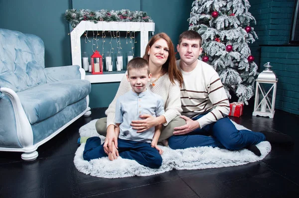 Famille, maman, papa et fils sont assis sur le sol et cheminée près de l'arbre de Noël . — Photo