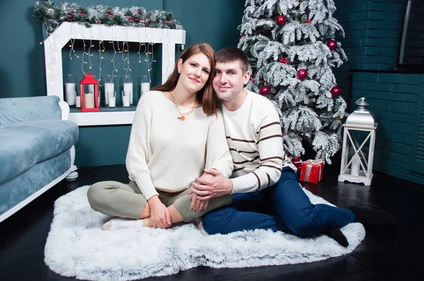 在圣诞树旁和壁炉旁的年轻貌美的夫妻 — 图库照片