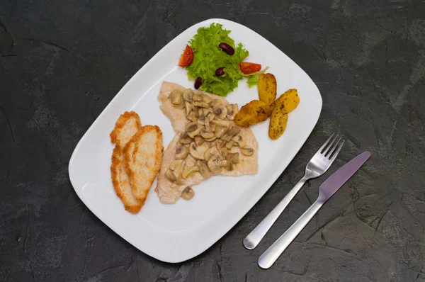 魚の切り身と煮込みキノコ,サラダ,揚げジャガイモとクルトン,暖かい灰色の背景に.おいしい伝統的なイタリア料理 — ストック写真
