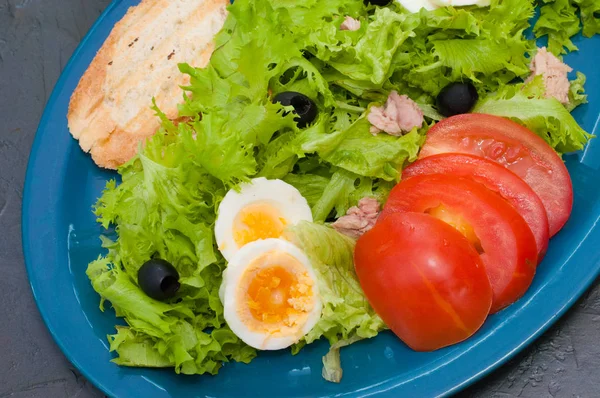 Σαλάτα με τόνο, βραστά αυγά, ελιές ντομάτας και κρουτόν σε μπλε πιάτο — Φωτογραφία Αρχείου