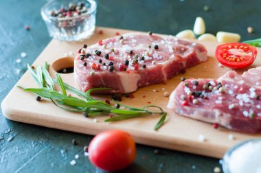 Biber ve tuz serpilmiş çiğ domuz eti doğranmış domates, sarımsak ve biberiye, biftek pişirme süreci.