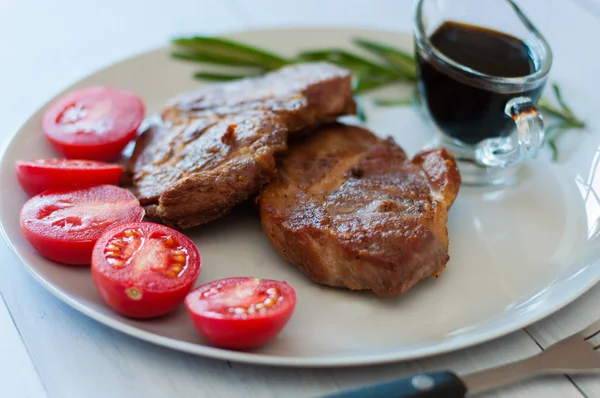 Chutné, šťavnaté, smažené masové steaky z vepřového nebo hovězího masa s omáčkou, kořením a rajčaty — Stock fotografie