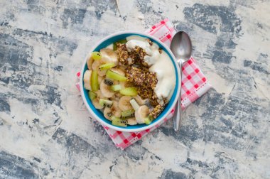 Granola, kivi, muz ve Yunan yoğurt gri beton arka plan üzerinde bir kase içinde, kırmızı bir peçete üzerinde, üstten alan görünümü kopyalayın. Kilo kaybı, doğru beslenme ve sağlıklı bir yaşam tarzı için Fitness diyet