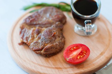 Soya sosu, biberiye ve domatesli ahşap bir tahtanın üzerinde pişmiş domuz eti.