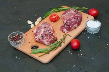 Kesme tahtasında çiğ et, tuz ve biber serpiştirilmiş, sarımsak, biberiye ve domates, üst görüş ve yan görüş.