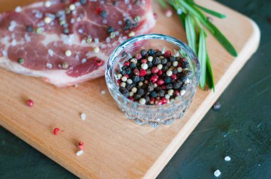 Düz uzanmış, üzerine biber ve tuz serpilmiş çiğ domuz eti doğranmış domates ve biberiye, biftek pişirme süreci.