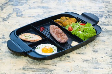 Kahvaltı, kızarmış biftek ya da pirzola, domatesli ve yeşil sebzeli salata, kızarmış ekmek, patates, yumurta manzaralı, açık arkaplan. Sağlıklı beslenme, diyet, menü, iyi beslenme.