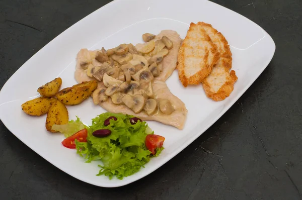 Balık filetosu, salata, kızarmış patates ve kızarmış ekmekle pişirilmiş mantar, sıcak gri bir arka planda. Lezzetli geleneksel İtalyan yemekleri. — Stok fotoğraf