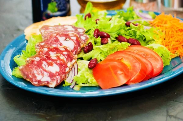 Salát s klobásou, rajčaty, fazolemi, mrkví, kořením, olivovým olejem nebo omáčkou. Restaurace podávající italská jídla — Stock fotografie