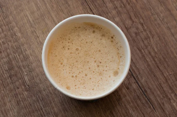 Cappuccino avec une délicieuse mousse dans une tasse en papier, vue sur le dessus, café à emporter — Photo