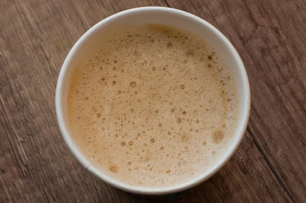 Cappuccino dengan busa lezat dalam cangkir kertas, top view, kopi untuk pergi — Stok Foto