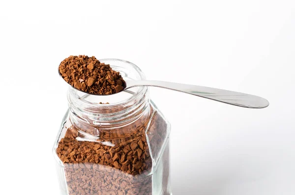 Instant coffee in spoon and a jar on a white background, granules closeup — 스톡 사진