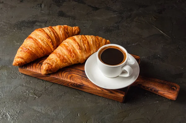 Кофе ристретто или эспрессо и круассаны на тёмном фоне, на деревянной доске — стоковое фото