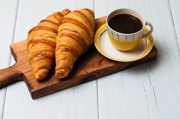 Espresso en coupe jaune vintage, croissants et cannelle sur planche de bois, sur fond clair, concept de déjeuner — Photo