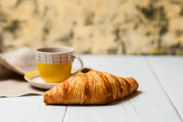 Espresso dans une tasse jaune vintage avec soucoupe et cuillère, sur une serviette en lin croissant sur fond clair, concept de déjeuner — Photo