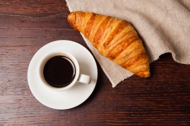 Lezzetli köy kahvaltısı. Beyaz fincanda kruvasan ve kahve, üst manzara, düz yatış.
