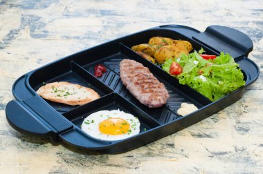 Kahvaltı, kızarmış biftek ya da pirzola, domatesli ve yeşil sebzeli salata, kızarmış ekmek, patates, yumurta manzaralı, açık arkaplan. Sağlıklı beslenme, diyet, menü, iyi beslenme.