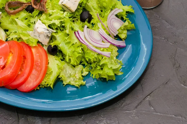 Salad with octopus or squid, cheese, tomato, olives, onions, spices and croutons, sauce or oil on blue plate