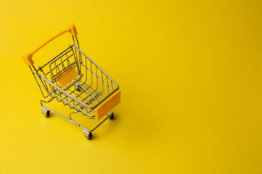Sarı arka planda alışveriş arabası. Süpermarket fiyat konsepti, tatil indirimleri