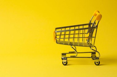 Sarı arka planda alışveriş arabası. Süpermarket fiyat konsepti, tatil indirimleri