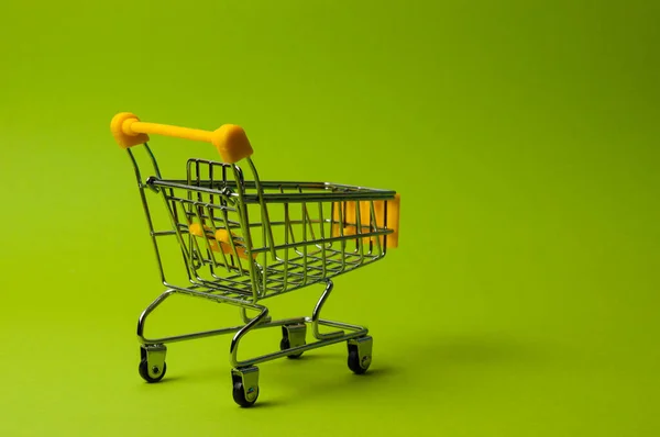 Trolley for shopping on green background. Supermarket food price concept, holiday discounts