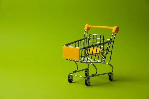 Trolley for shopping on green background. Supermarket food price concept, holiday discounts