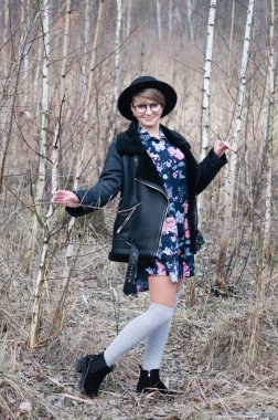 Baharın başında ya da sonbaharın sonunda huş ağaçları arasında poz veren şapkalı güzel bir kadın.