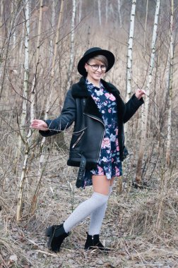 Baharın başında ya da sonbaharın sonunda huş ağaçları arasında poz veren şapkalı güzel bir kadın.