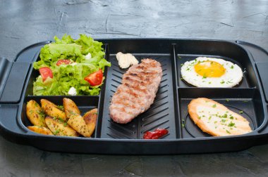 Kahvaltı, pirzola ya da biftek, domates salatası, kızarmış patates ve kızarmış yumurta.
