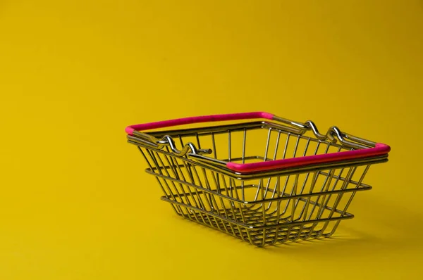 Shopping basket on yellow background. Supermarket food price concept.