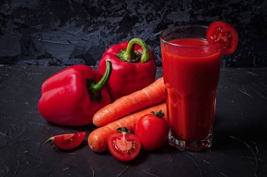 Koyu beton bir yüzeyde bir bardak meyve suyu ile sebzeler