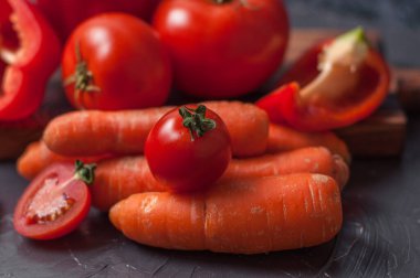 Sebzeler, havuçlar, biberler ve domatesler koyu gri betona yakın çekim.