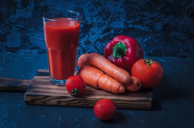 Tahtada meyve suyu, sebze, domates, havuç ve biber. Durgun hayat koyu renklerde