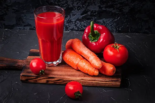 Gemüsesaft im Glas und Gemüse auf dem Schneidebrett: Möhren, Paprika und Tomaten — Stockfoto