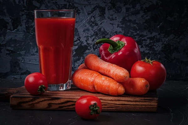 Gemüsesaft im Glas und Gemüse auf dem Schneidebrett: Möhren, Paprika und Tomaten — Stockfoto