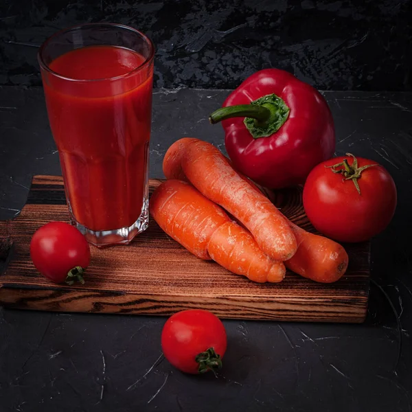 Gemüsesaft im Glas und Gemüse auf dem Schneidebrett: Möhren, Paprika und Tomaten. Rechteckiges Rahmenformat — Stockfoto